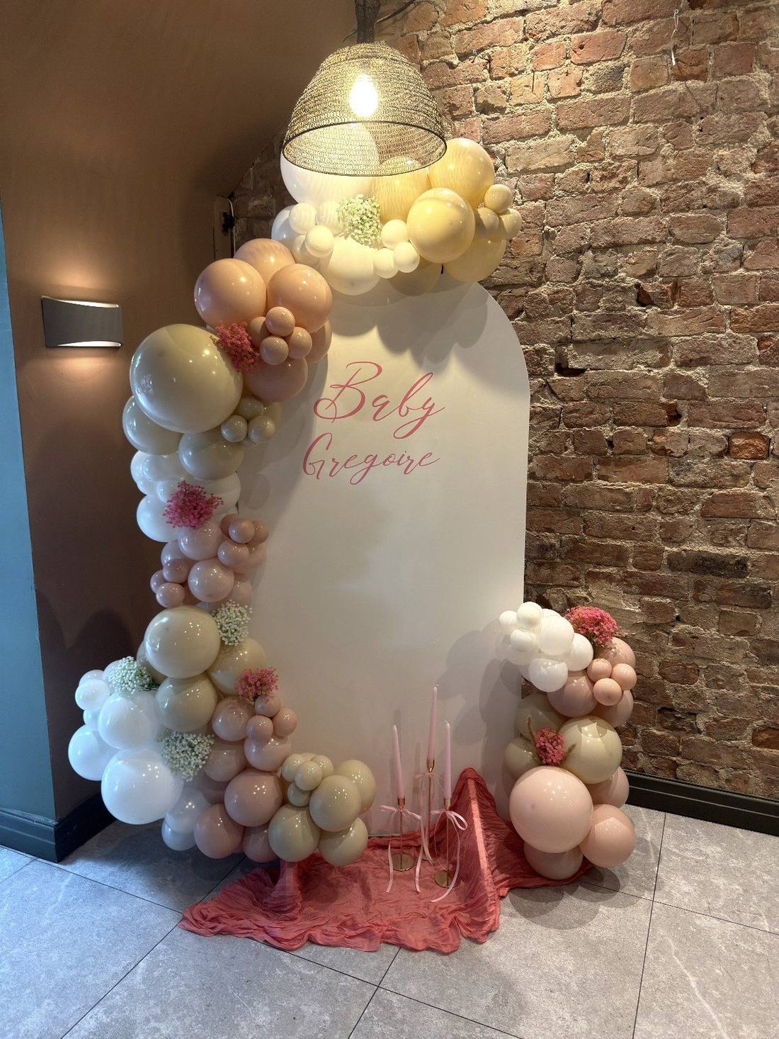 Arch balloon display with florals and pendant lighting for a baby shower celebration