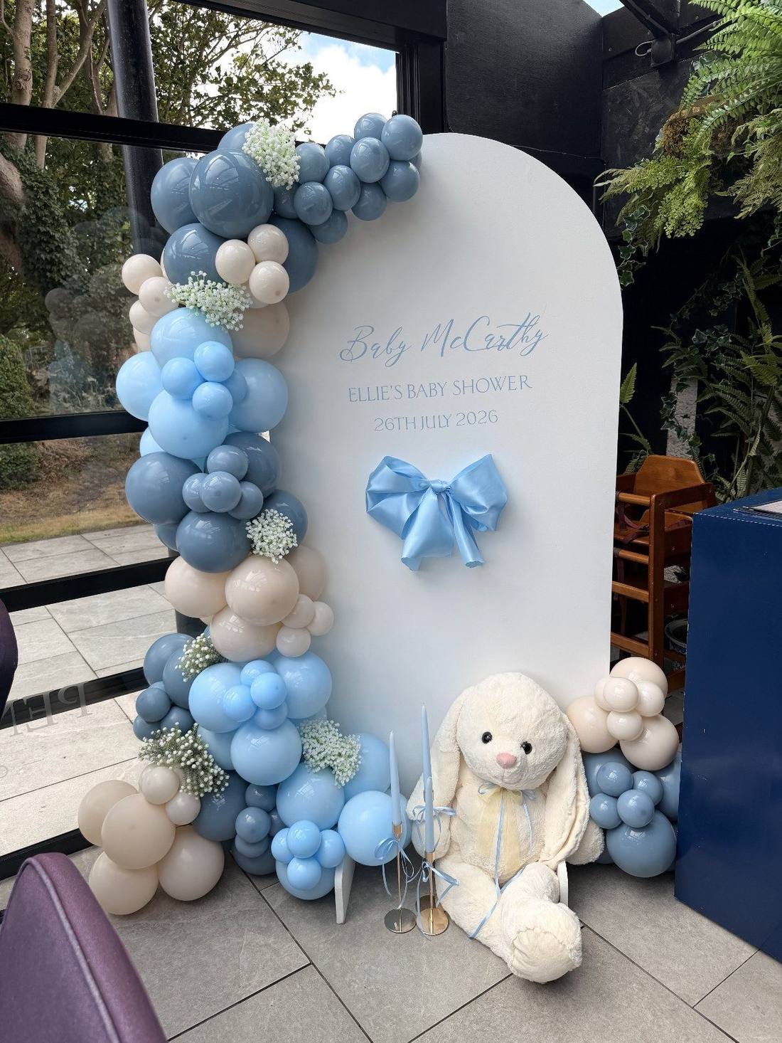 Blue and cream balloon arch display with florals for a baby shower