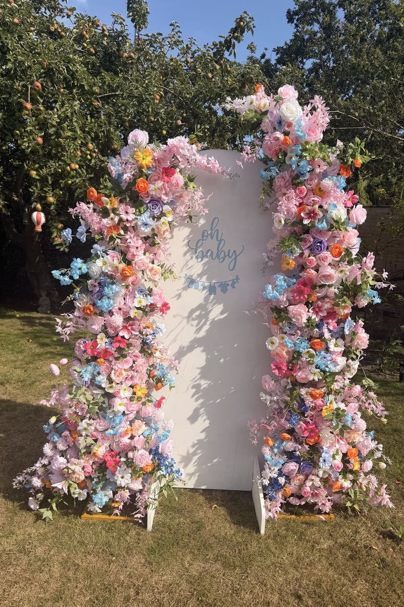 Broken floral arch display framing an Oh Baby sail board sign