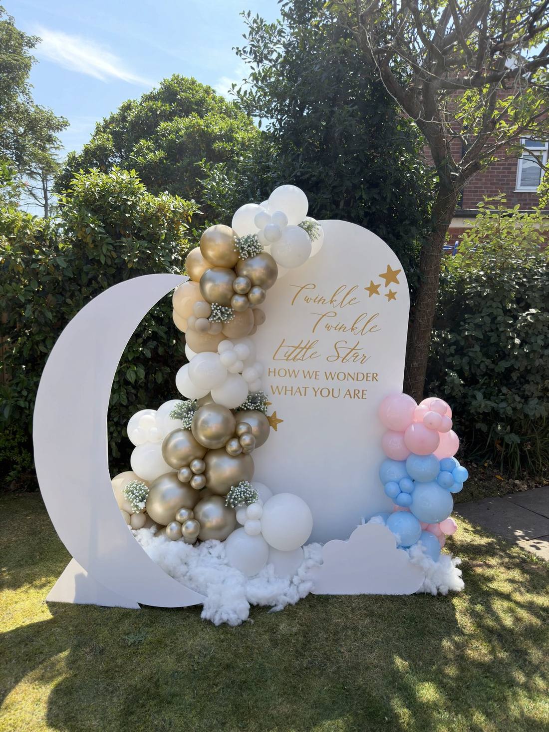 Moon and cloud shaped balloon display in gold, pink and blue for a gender reveal party